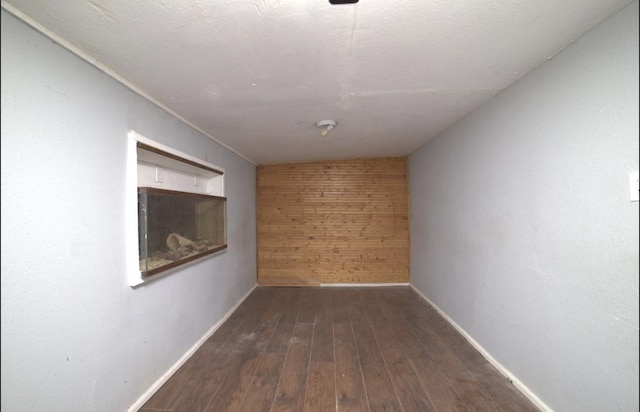 empty room with dark hardwood / wood-style flooring and wooden walls