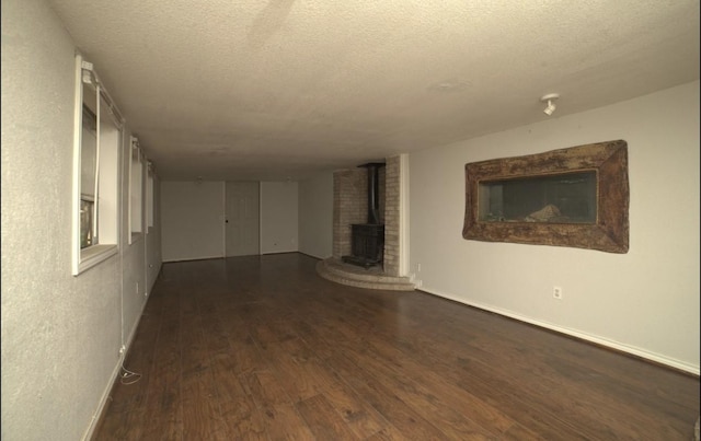 unfurnished living room with a textured ceiling, dark hardwood / wood-style flooring, and a wood stove