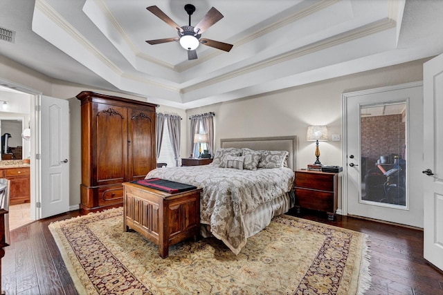 bedroom with ensuite bath, ceiling fan, ornamental molding, a tray ceiling, and dark hardwood / wood-style flooring