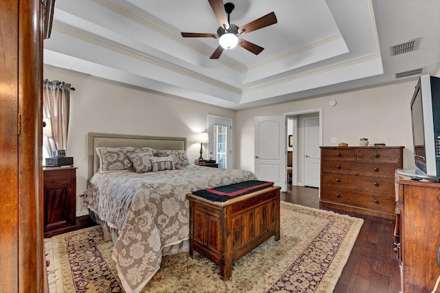 bedroom with ceiling fan, a raised ceiling, dark wood-type flooring, and multiple windows