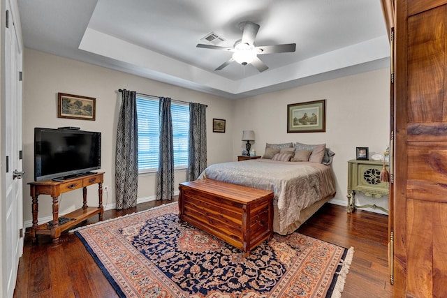 bedroom with a raised ceiling, ceiling fan, and dark hardwood / wood-style flooring