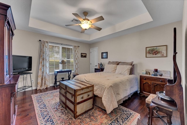 bedroom with a tray ceiling, ceiling fan, and dark hardwood / wood-style flooring