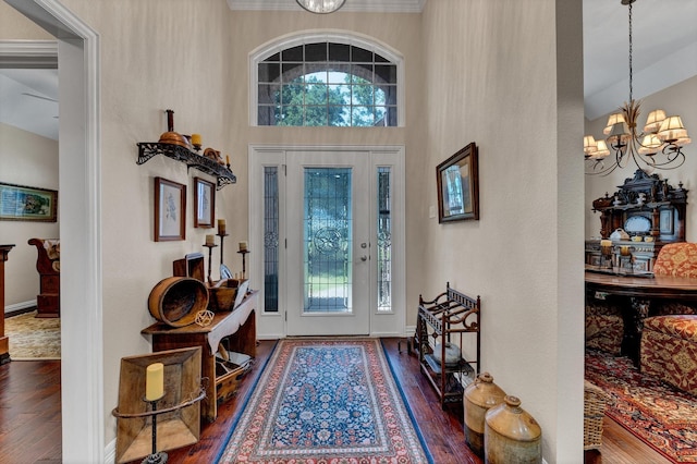 entryway with wood-type flooring, a towering ceiling, and an inviting chandelier