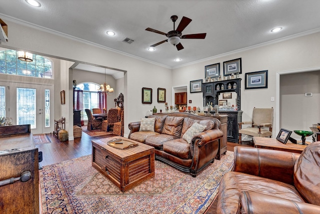 living room with ceiling fan with notable chandelier, hardwood / wood-style flooring, and crown molding