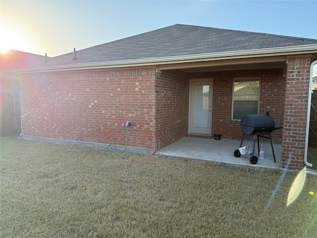 back house at dusk featuring a yard and a patio