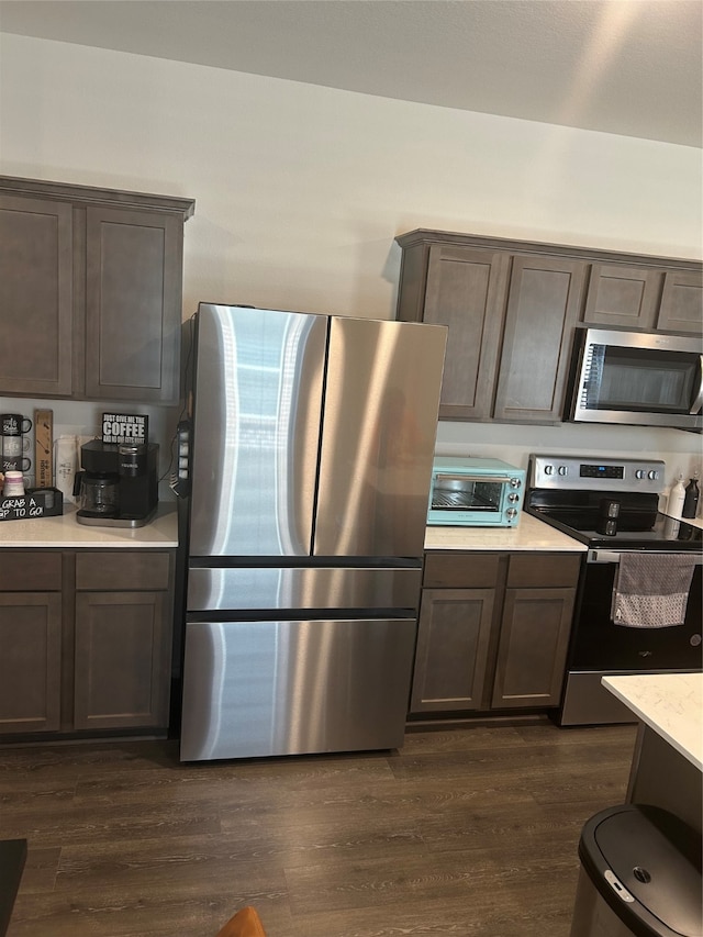 kitchen featuring dark wood-type flooring, appliances with stainless steel finishes, and dark brown cabinetry