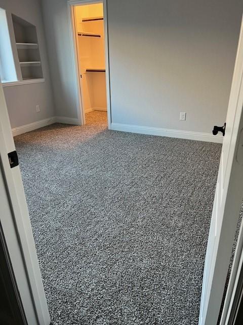 unfurnished bedroom with carpet flooring, a spacious closet, and a closet