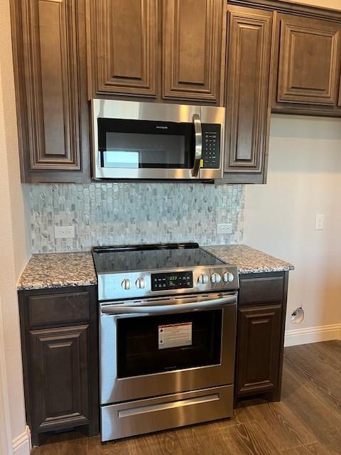 kitchen featuring light stone countertops, appliances with stainless steel finishes, tasteful backsplash, and dark wood-type flooring