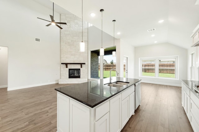 kitchen featuring a fireplace, visible vents, open floor plan, a sink, and dishwasher