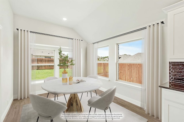 dining room with light hardwood / wood-style floors and vaulted ceiling