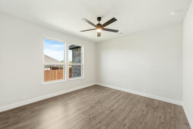 empty room with a ceiling fan, baseboards, visible vents, and wood finished floors