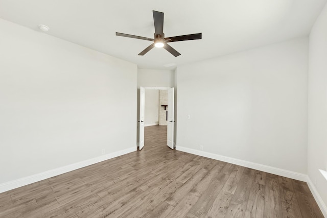 spare room featuring wood finished floors, a ceiling fan, and baseboards