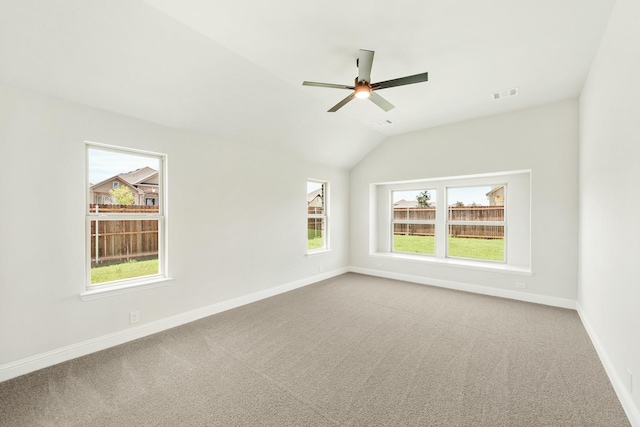 carpeted spare room featuring lofted ceiling, visible vents, baseboards, and a ceiling fan