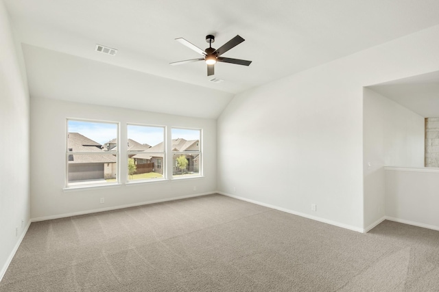 spare room with baseboards, visible vents, a ceiling fan, vaulted ceiling, and carpet flooring