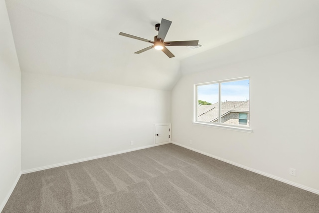 empty room featuring carpet, visible vents, vaulted ceiling, and baseboards