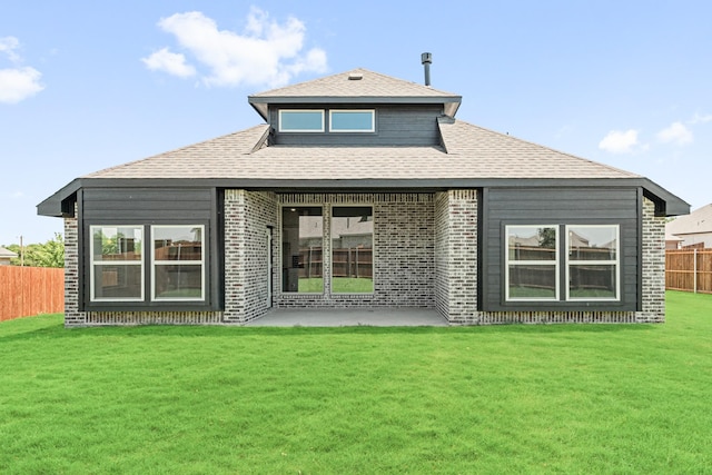 back of property with a yard, brick siding, a patio, and fence