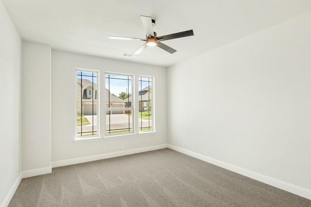 carpeted empty room with a ceiling fan and baseboards