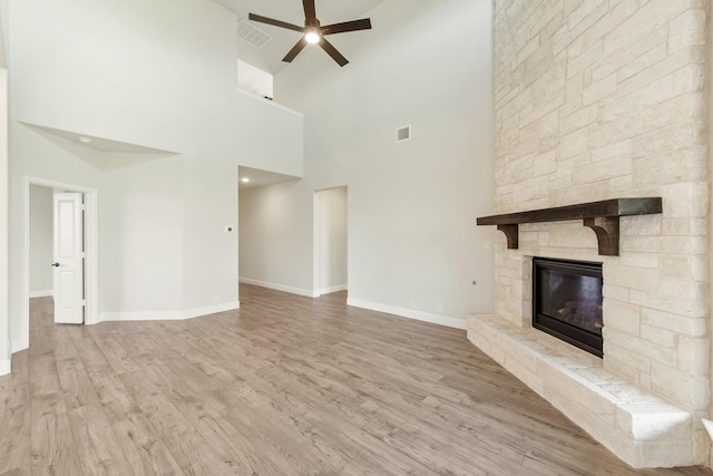 unfurnished living room featuring ceiling fan, visible vents, wood finished floors, and a stone fireplace