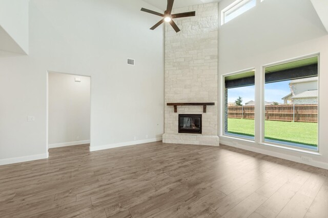 unfurnished living room featuring visible vents, a fireplace, baseboards, and wood finished floors