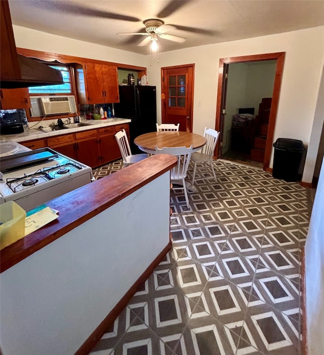 kitchen featuring gas range gas stove, black refrigerator, and ceiling fan