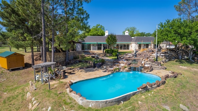 view of pool with pool water feature, a shed, and a patio