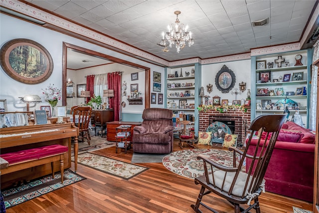 living area featuring wood-type flooring, built in shelves, a chandelier, and a fireplace