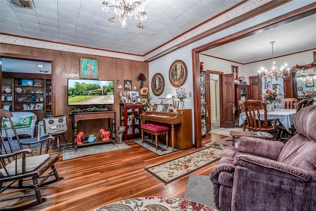 living room featuring a chandelier, ornamental molding, hardwood / wood-style flooring, and built in shelves