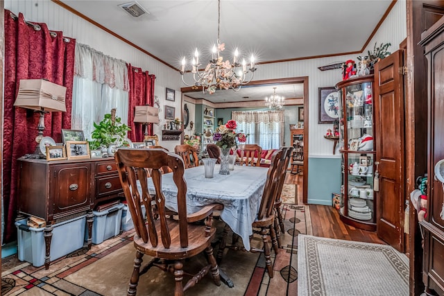 dining space featuring wood-type flooring, ornamental molding, and a chandelier