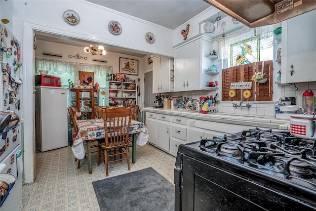 2252 Cleveland St, Paris, TX 75460 - kitchen featuring black range with gas cooktop, refrigerator, light countertops, white cabinets, and open shelves