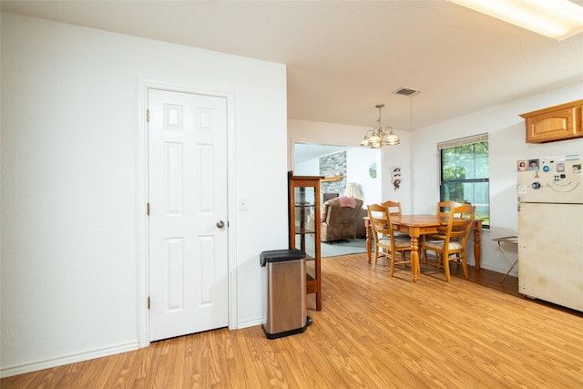 dining room with light hardwood / wood-style floors and a notable chandelier