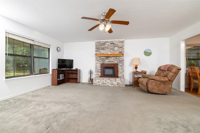 living room featuring ceiling fan, carpet floors, a textured ceiling, and a brick fireplace