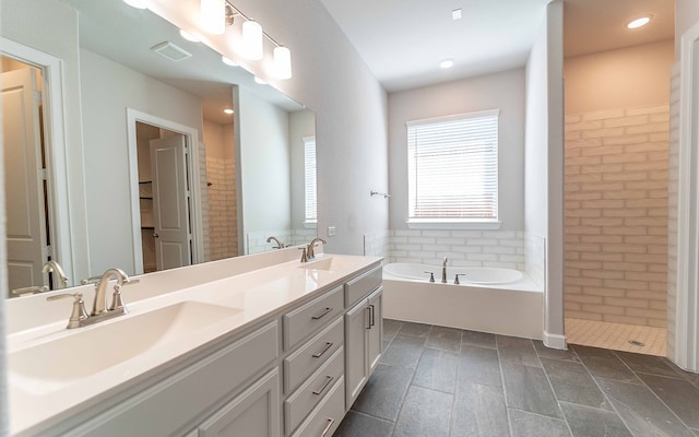 bathroom featuring a bath to relax in, vanity with extensive cabinet space, dual sinks, and tile floors