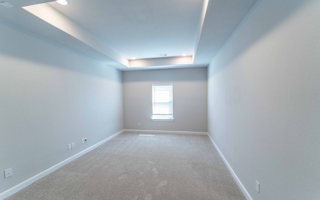 empty room with carpet floors and a raised ceiling