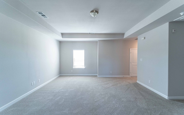 carpeted spare room featuring a tray ceiling