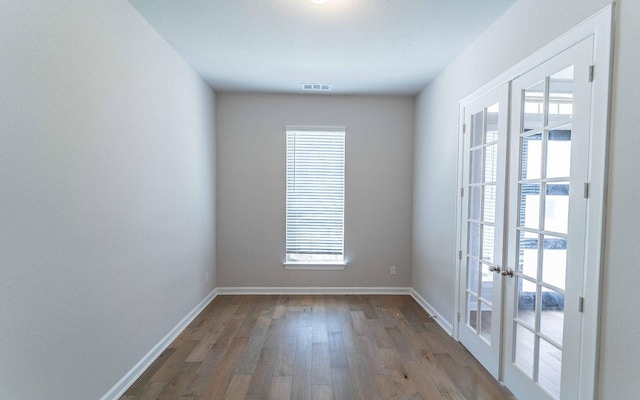 unfurnished room featuring plenty of natural light, french doors, visible vents, and wood finished floors