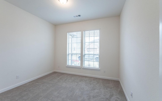 spare room with carpet, plenty of natural light, visible vents, and baseboards