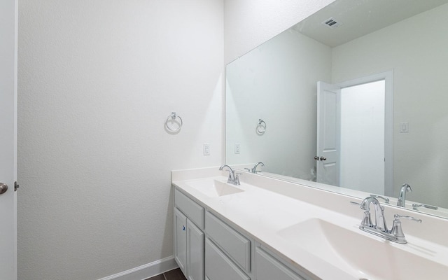 full bath featuring double vanity, a sink, visible vents, and baseboards