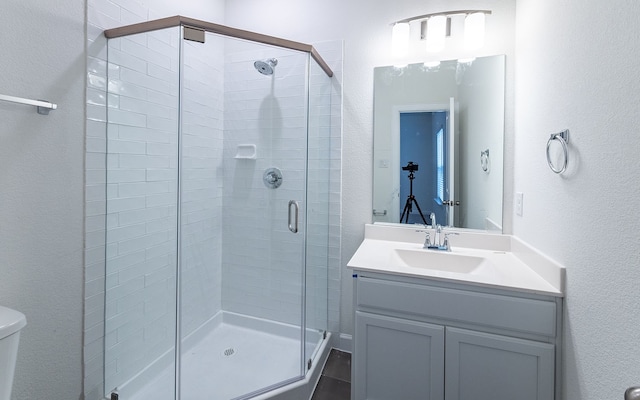 bathroom with a shower with shower door, toilet, and vanity with extensive cabinet space