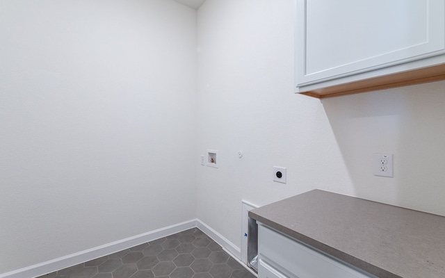 clothes washing area with gas dryer hookup, washer hookup, electric dryer hookup, dark tile flooring, and cabinets