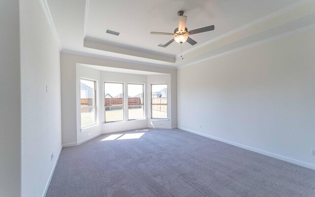 empty room featuring ornamental molding, carpet floors, ceiling fan, and a raised ceiling