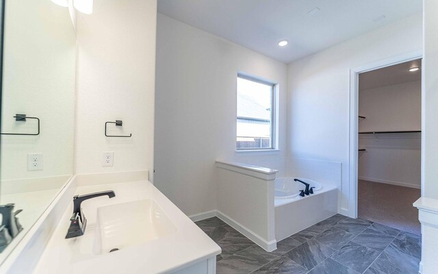 bathroom with a bath, tile floors, and vanity