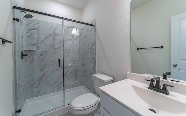 bathroom featuring a shower with door, toilet, and large vanity