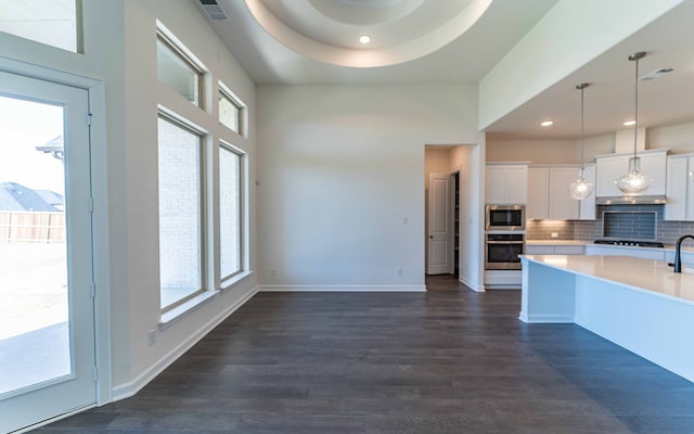 kitchen with white cabinetry, hanging light fixtures, stainless steel appliances, dark hardwood / wood-style floors, and backsplash