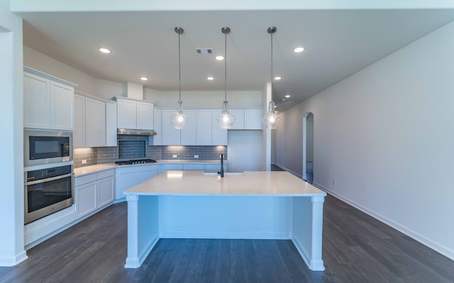 kitchen with dark wood-type flooring, appliances with stainless steel finishes, white cabinetry, and tasteful backsplash