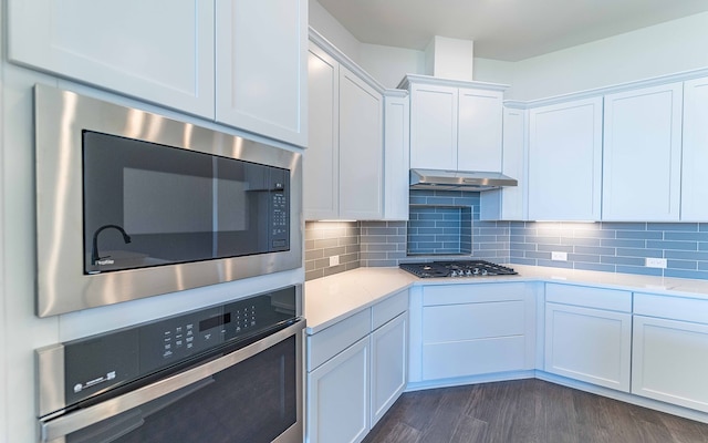 kitchen featuring dark hardwood / wood-style floors, light stone countertops, tasteful backsplash, stainless steel appliances, and white cabinets