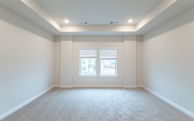 carpeted spare room with a tray ceiling