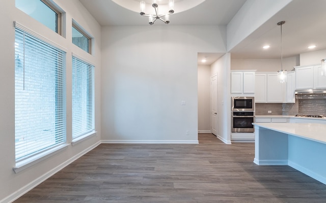 kitchen featuring appliances with stainless steel finishes, hanging light fixtures, backsplash, and hardwood / wood-style floors