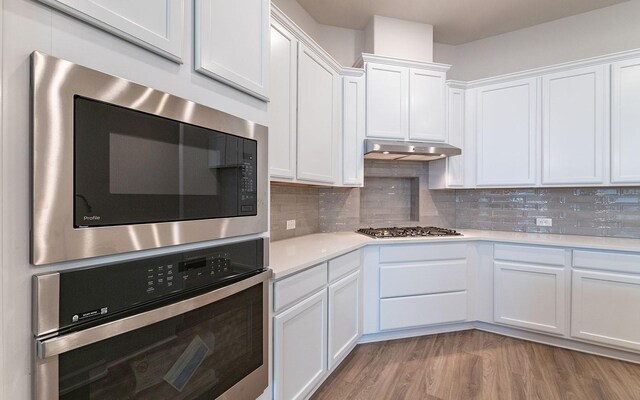 kitchen featuring stainless steel appliances, tasteful backsplash, white cabinets, and light wood-type flooring