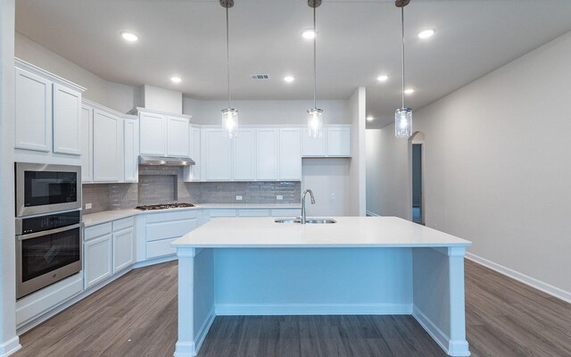 kitchen featuring hanging light fixtures, hardwood / wood-style floors, tasteful backsplash, and appliances with stainless steel finishes