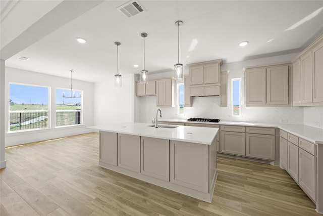 kitchen with decorative light fixtures, light wood-type flooring, sink, and decorative backsplash